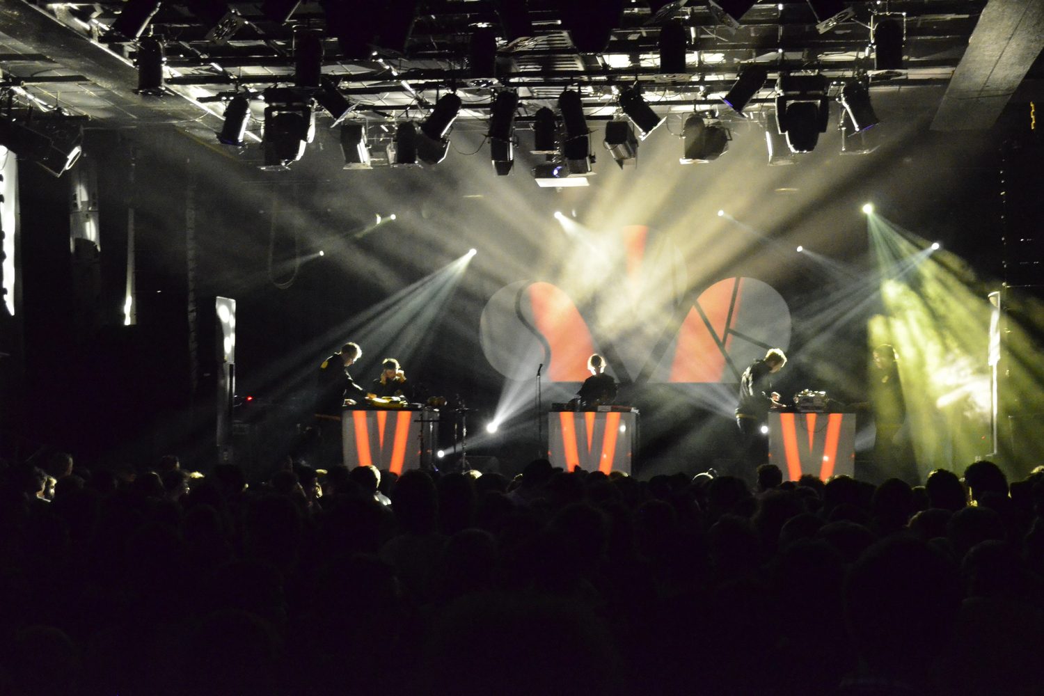 Festival main stage lit in beams and haze over a full crowd